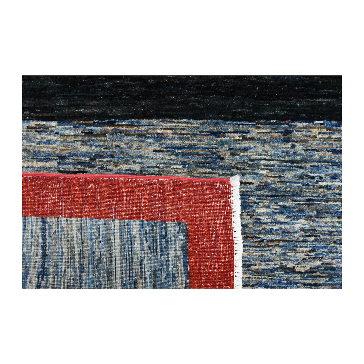 Folded-corner detail of Afghan Gabbeh rug showing the reverse weave, red border, blue field and pale fringe
