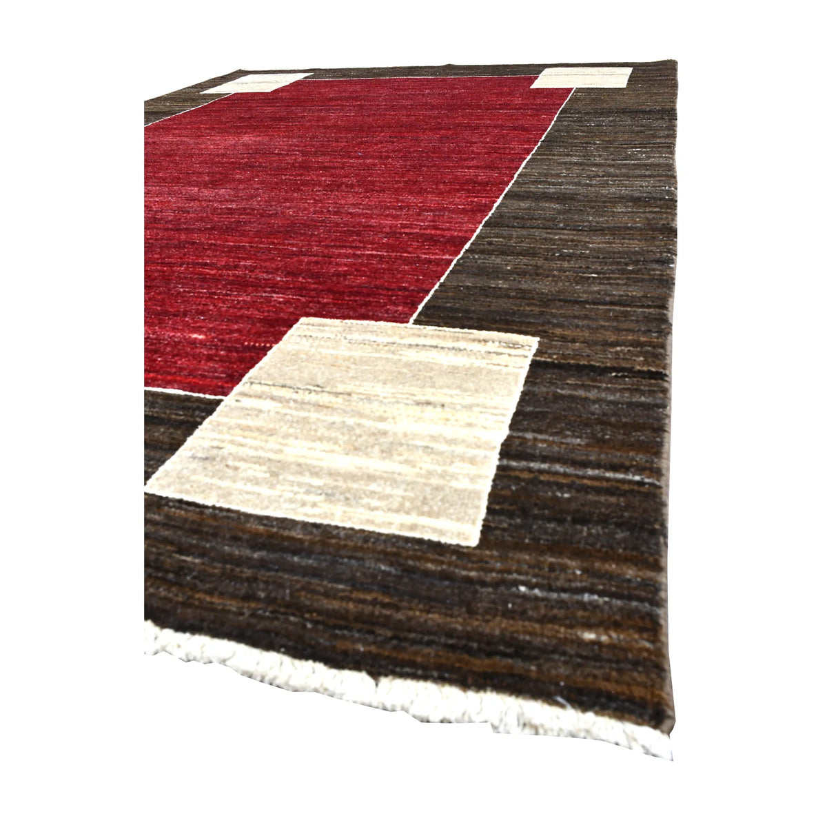 Angled view of Afghan Gabbeh wool rug showing its red field, broad brown frame, off-white corner block and pale fringe