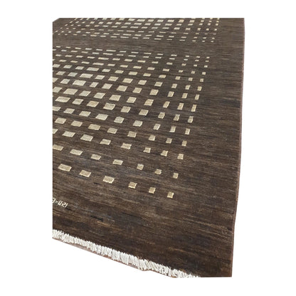 Angled close-up of Afghan Gabbeh rug showing the ivory square lattice pattern, dark brown border and fringe edge