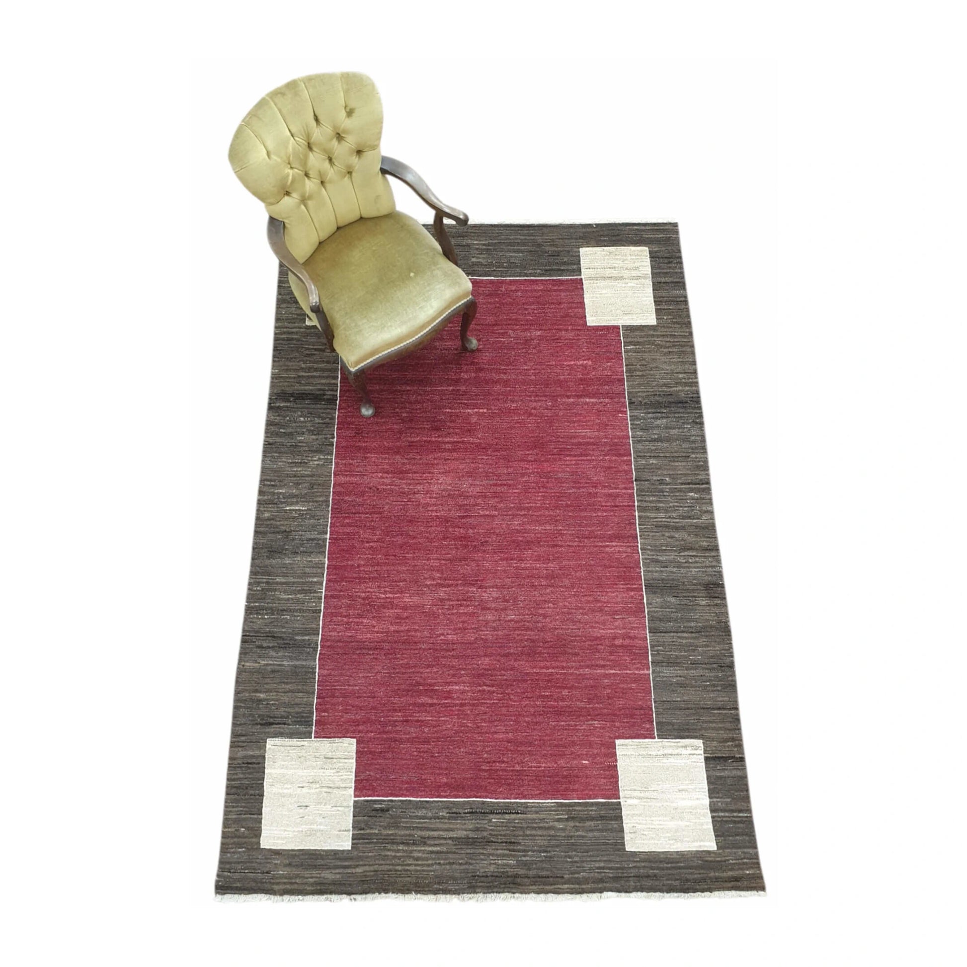 Lifestyle view of Afghan Gabbeh wool rug with red field, charcoal-brown border and off-white corner motifs, 243 x 162 cm