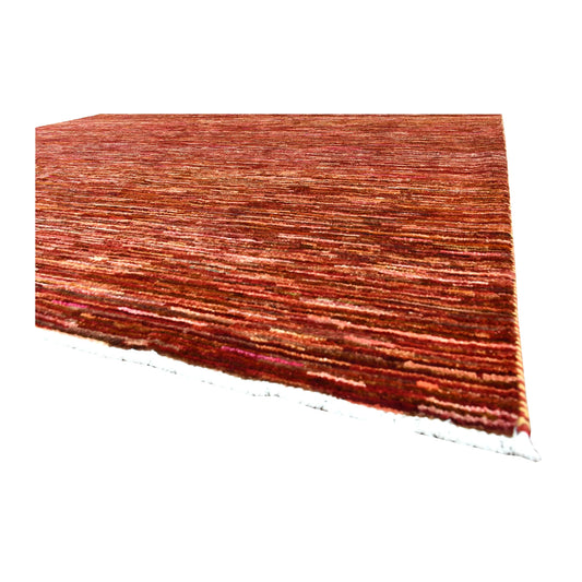 Corner detail of Afghan Gabbeh wool rug showing rust-red pile, fine tonal bands and ivory fringe