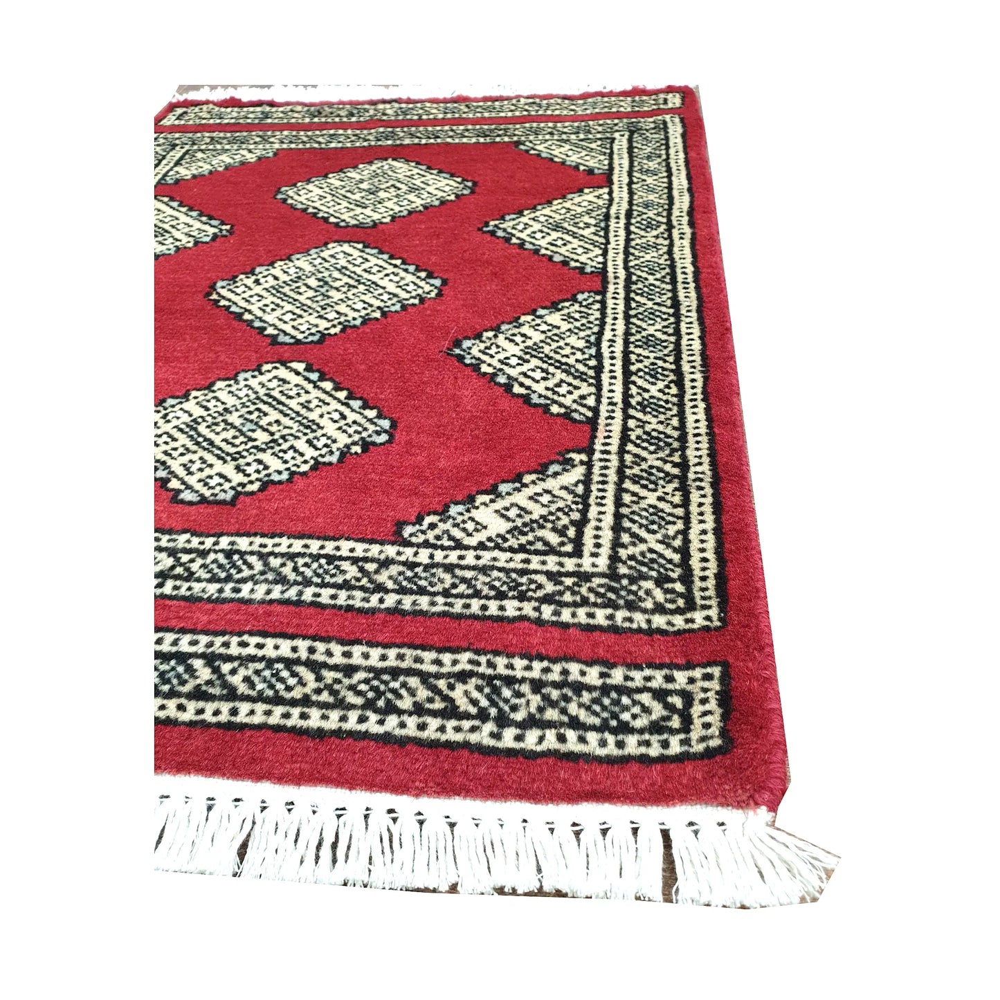 Angled fringe and border detail of Afghan Jaldar wool rug showing red pile, ivory diamond motifs and dark edging