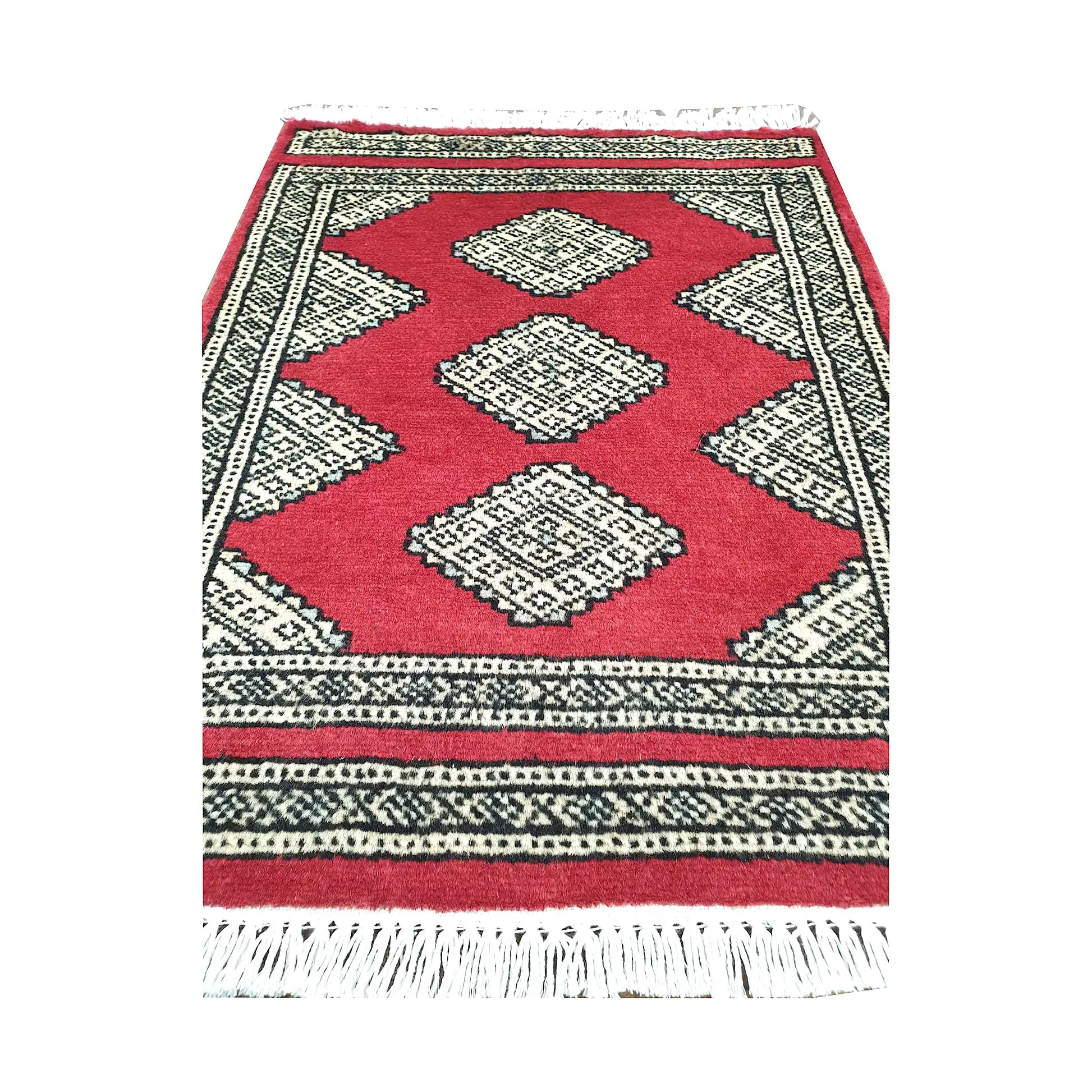 Red field and border detail of Afghan Jaldar wool rug showing ivory diamond medallions and geometric border