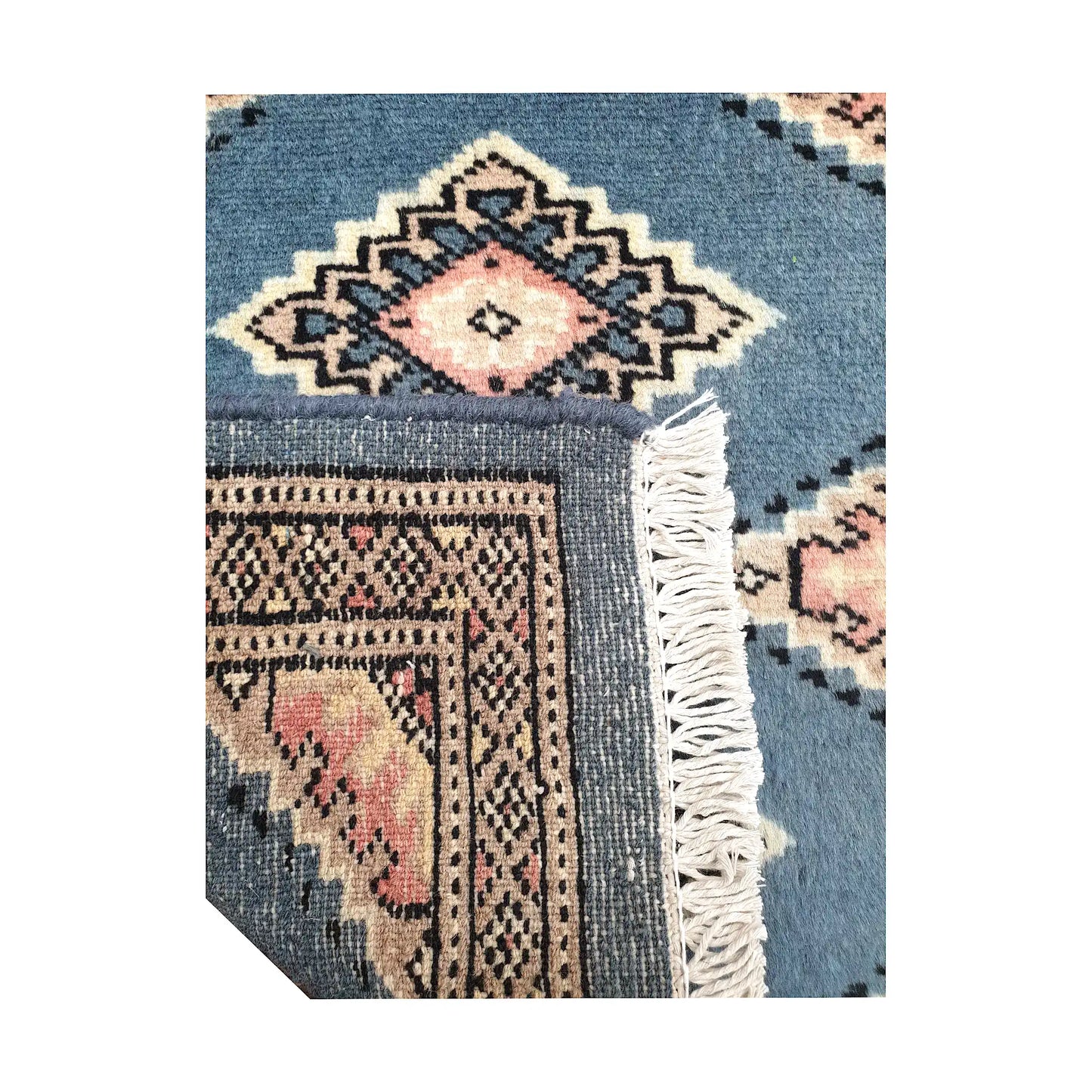 Folded corner detail of Afghan Jaldar wool rug showing the back of the rug, fringe and blue-grey front pattern