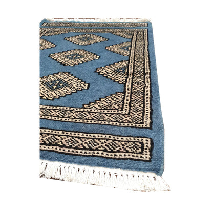 Angled fringe and border detail of Afghan Jaldar wool rug showing blue pile, ivory diamond motifs and dark geometric edging