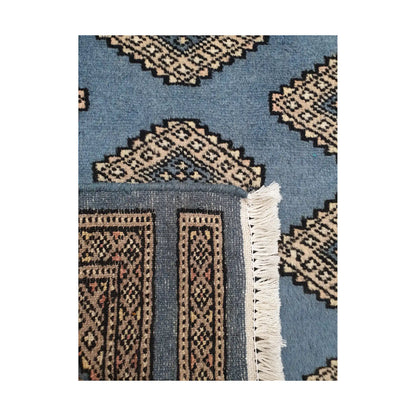 Folded corner detail of Afghan Jaldar wool rug showing the back of the rug, fringe and blue front pattern