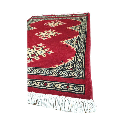 Angled fringe and border detail of Afghan Jaldar wool rug showing red pile, ivory diamond motifs and dark geometric edging