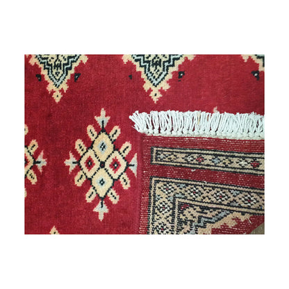 Folded corner detail of Afghan Jaldar wool rug showing the back of the rug, fringe and red front pattern