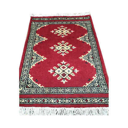 Red field and border detail of Afghan Jaldar wool rug showing ivory diamond medallions and traditional border pattern