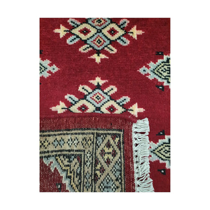 Folded corner detail of Afghan Jaldar wool rug showing the back of the rug, fringe and red front pattern