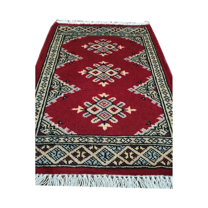 Red field and border detail of Afghan Jaldar wool rug showing ivory diamond medallions and traditional border pattern
