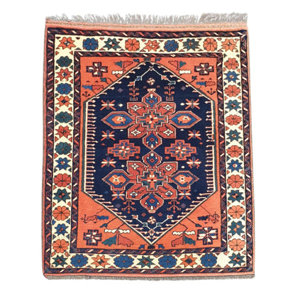 Full view of Afghan Karghai hand-knotted wool rug with warm orange field, navy medallion and cream floral border, 138 x 108 cm