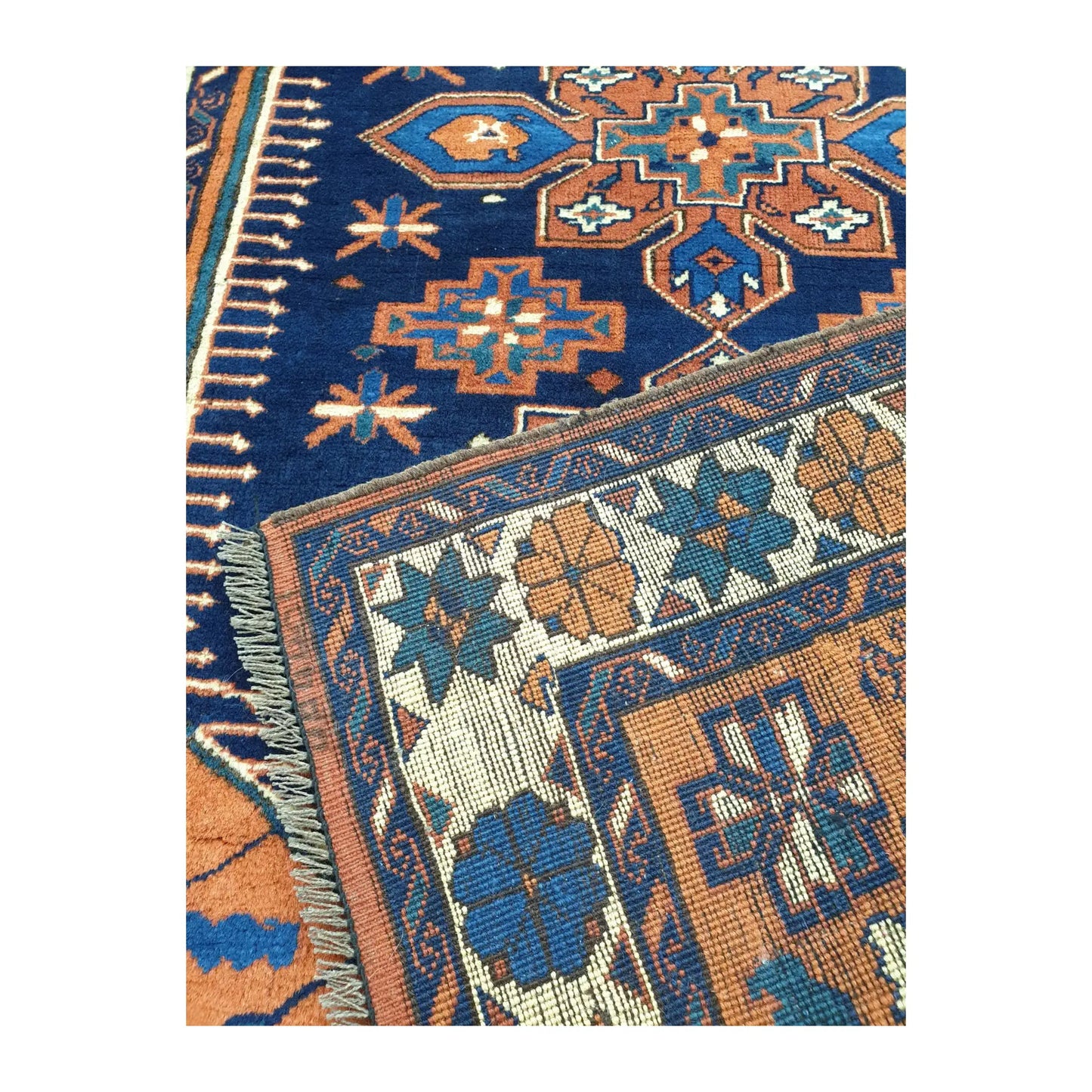 Folded corner detail of Afghan Karghai rug showing the navy patterned field, border and reverse side