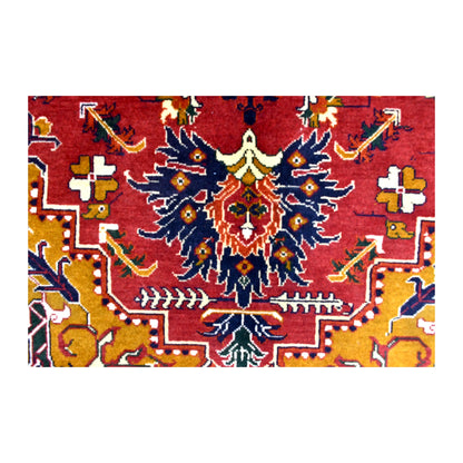 Field detail of Afghan Karghai rug showing a dark-blue floral motif against deep red with golden-ochre sections