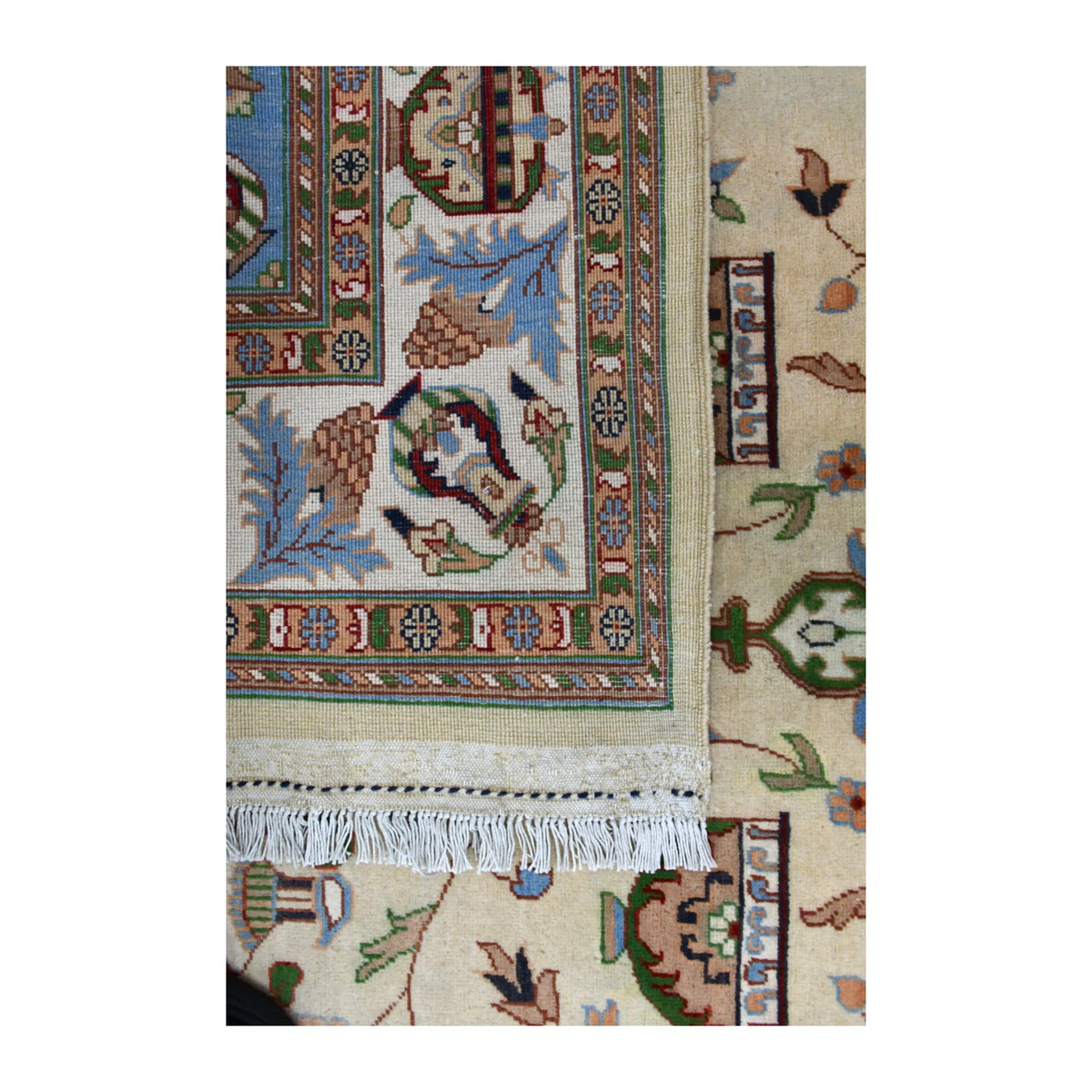 Folded-corner detail showing the Afghan Karghai rug’s paler patterned reverse, white fringe and floral front