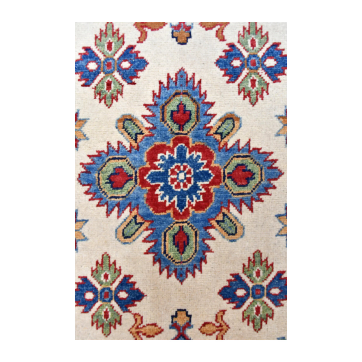 Close-up of a blue and red floral-geometric medallion with green accents on the Kazak runner’s cream field