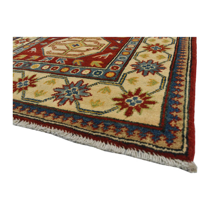 Angled corner and fringe view of Afghan Kazak wool rug showing cream field, red border detail and light fringe