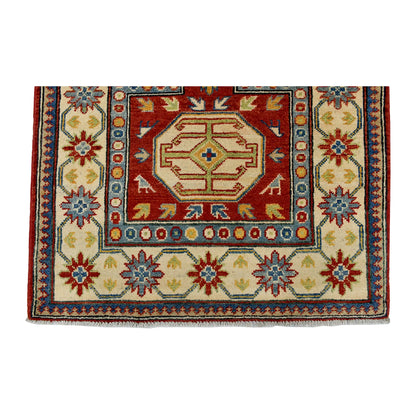End field and border detail of Afghan Kazak wool rug showing cream ground, red motifs, blue accents and patterned border