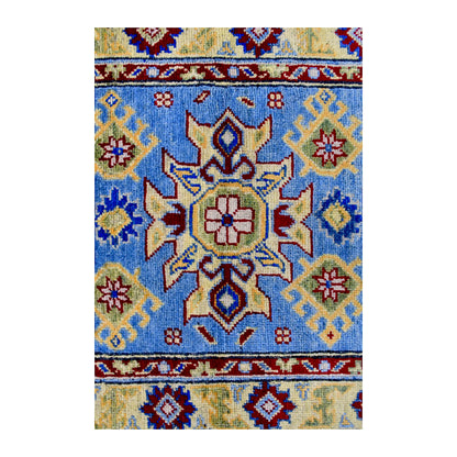 Central medallion detail of Afghan Kazak wool rug showing light blue field with red, cream, yellow and navy geometric motifs