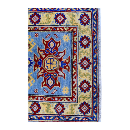 End medallion and border detail of Afghan Kazak hand-knotted wool rug showing light blue field, red motifs and patterned border