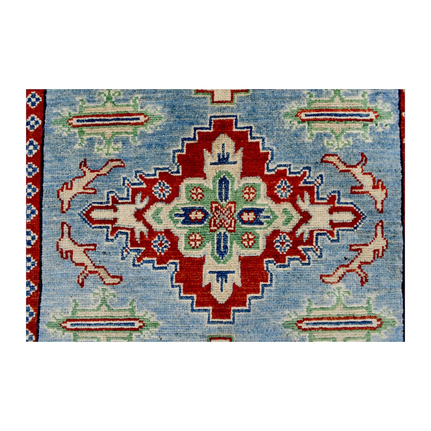 Central medallion detail of Afghan Kazak wool rug showing red, ivory, navy and muted green geometric motifs
