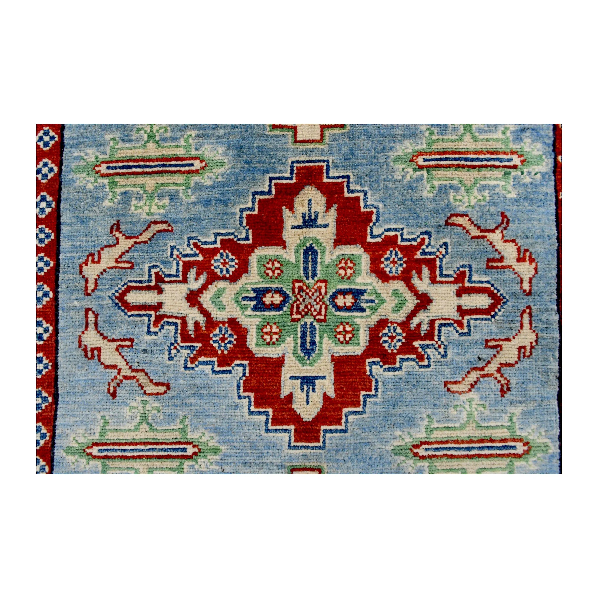 Central medallion detail of Afghan Kazak wool rug showing red, ivory, navy and muted green geometric motifs