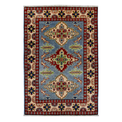 Full view of Afghan Kazak hand-knotted wool rug with light blue field, geometric medallions and red border, 150 x 102 cm