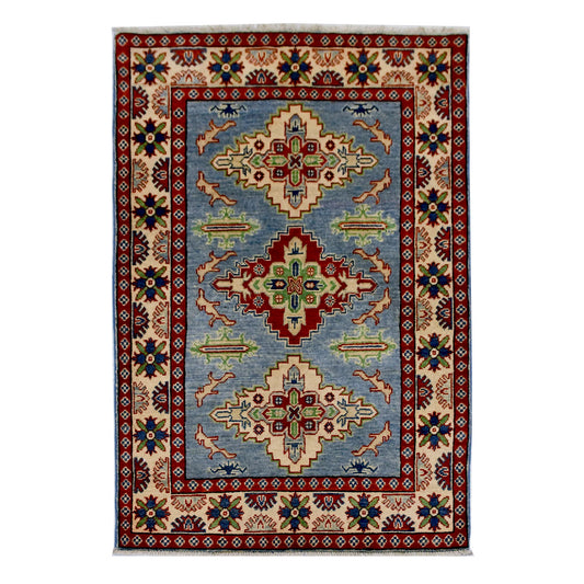 Full view of Afghan Kazak hand-knotted wool rug with light blue field, geometric medallions and red border, 150 x 102 cm