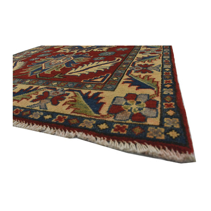 Angled corner and fringe view of Afghan Kazak wool rug showing red field, cream border and light fringe