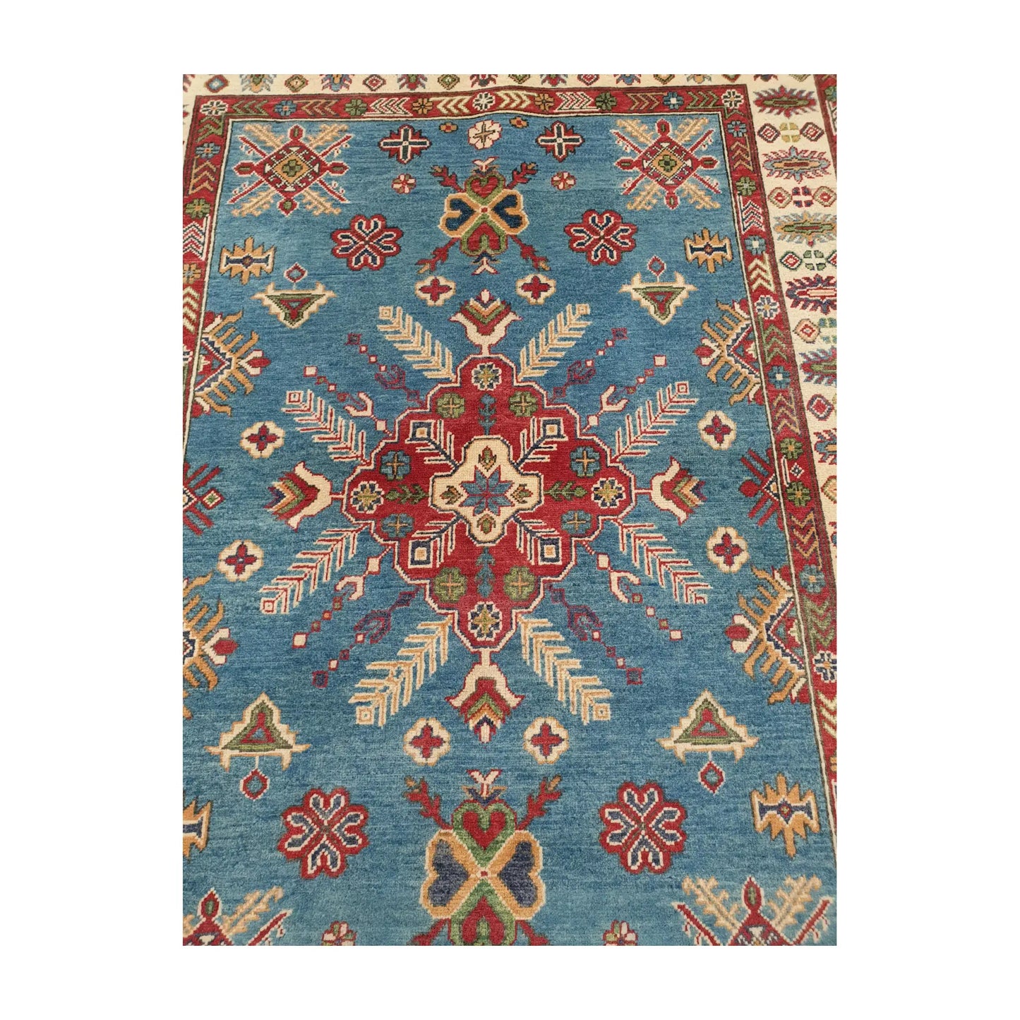 Central medallion detail of Afghan Kazak wool rug with geometric motifs on blue field