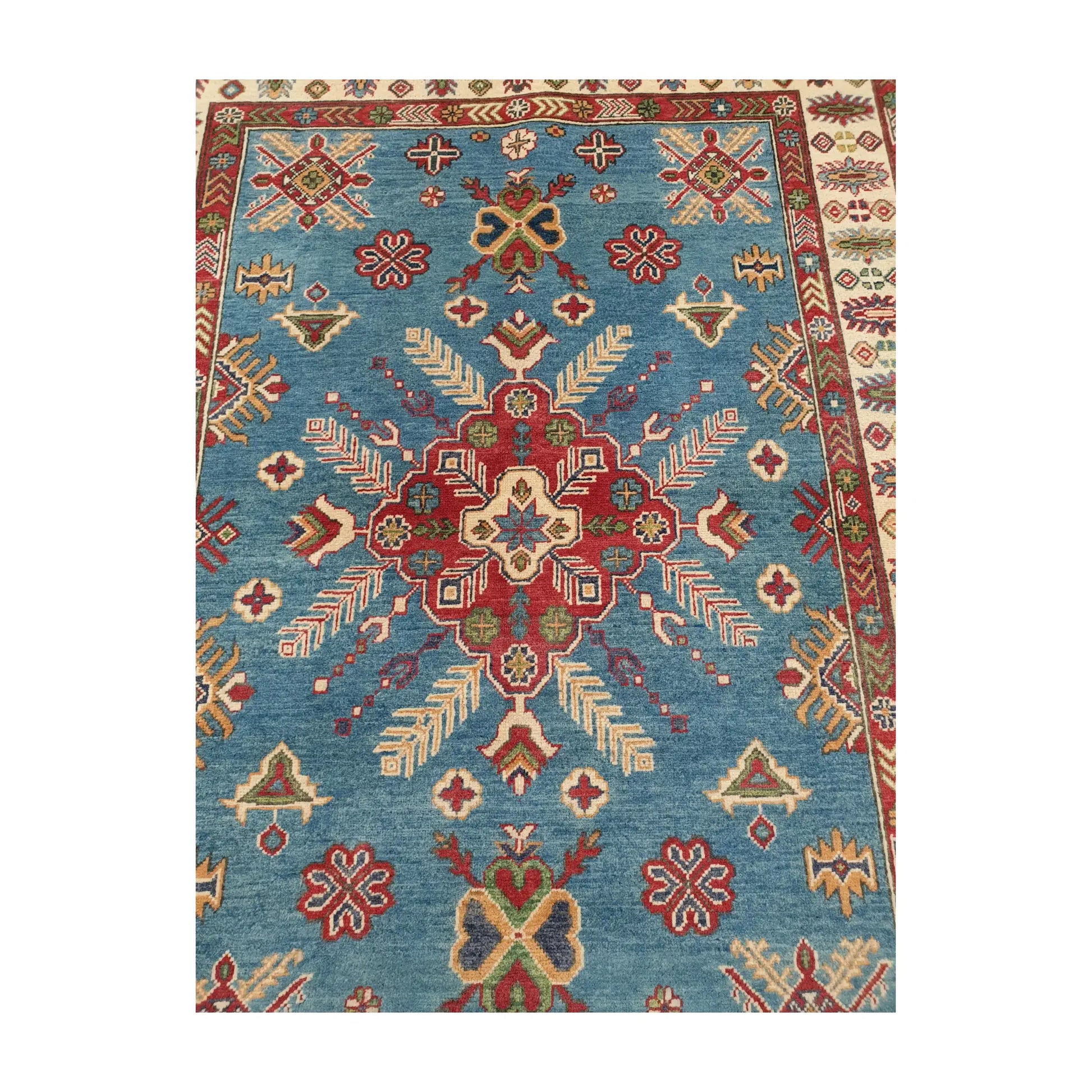 Central medallion detail of Afghan Kazak wool rug with geometric motifs on blue field