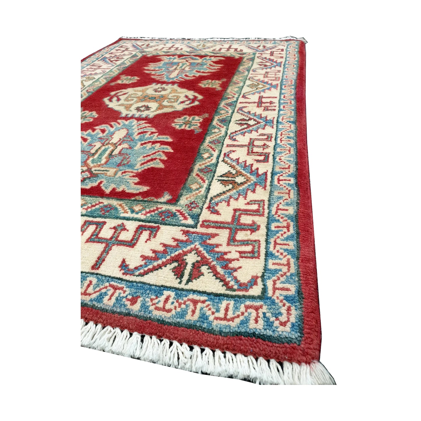 Angled corner and fringe view of Afghan Kazak wool rug showing red field, cream angular border and light fringe
