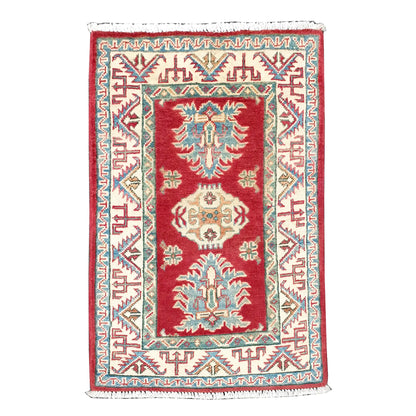Full view of Afghan Kazak hand-knotted wool rug with red field, cream geometric border and teal-blue stylised motifs, 87 x 62 cm