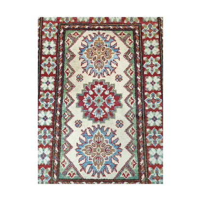 Detail of Afghan Kazak hand-knotted wool rug showing cream centre field, geometric medallions and framed border, 88 x 58 cm