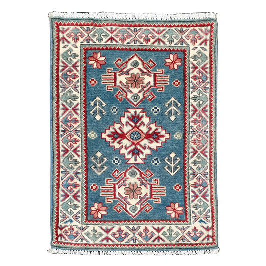 Full view of Afghan Kazak hand-knotted wool rug with blue field, central geometric medallion and cream patterned border, 90 x 61 cm