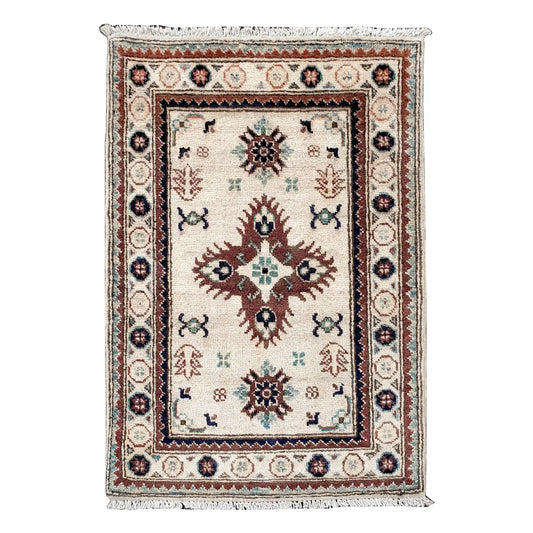 Full view of Afghan Kazak hand-knotted wool rug with ivory field, central geometric medallion and framed border, 90 x 64 cm