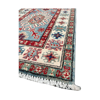Angled corner and fringe view of Afghan Kazak wool rug showing blue field, off-white border, red detail and light fringe
