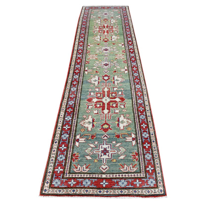 Full view of Afghan Kazak hand-knotted wool runner with a sage-green field, red geometric medallions and layered border, 327 x 83 cm