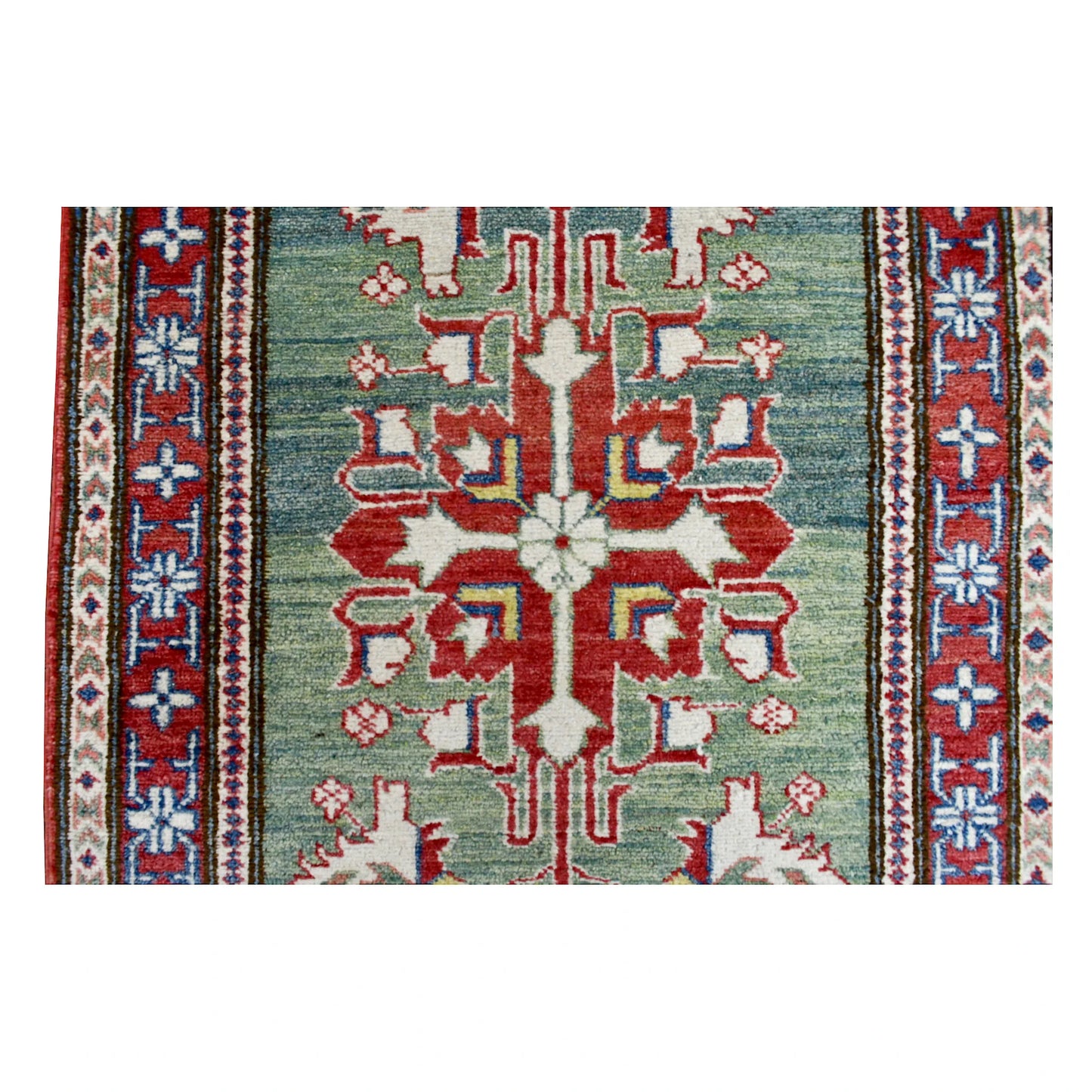 Close-up of a large red geometric medallion on the sage-green field of the Afghan Kazak runner