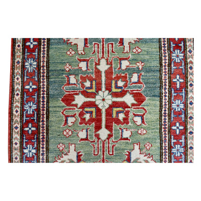 Close-up of a large red geometric medallion on the sage-green field of the Afghan Kazak runner