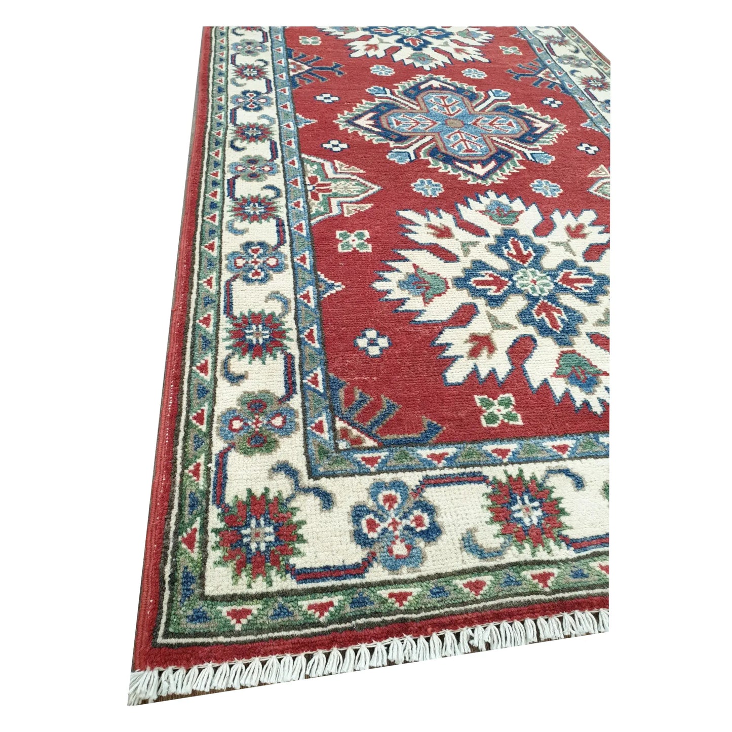 Close-up of Afghan Kazak wool runner rug corner showing light green border, red field and hand-knotted texture