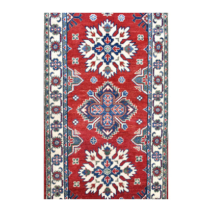 Field detail of Afghan Kazak runner showing alternating ivory starburst and blue-red medallions across the red ground