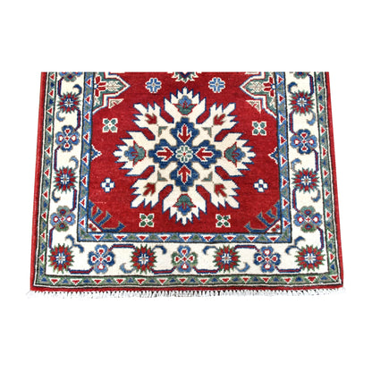 Fringe-end detail of Afghan Kazak runner showing an ivory starburst medallion, flowering border and white fringe