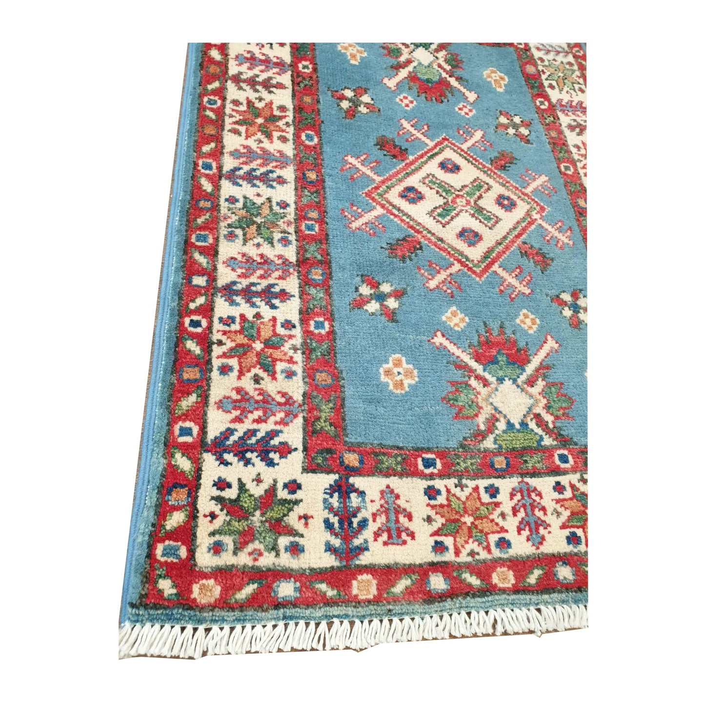Angled corner detail of Afghan Kazak rug showing blue field motifs, layered border and visible fringe
