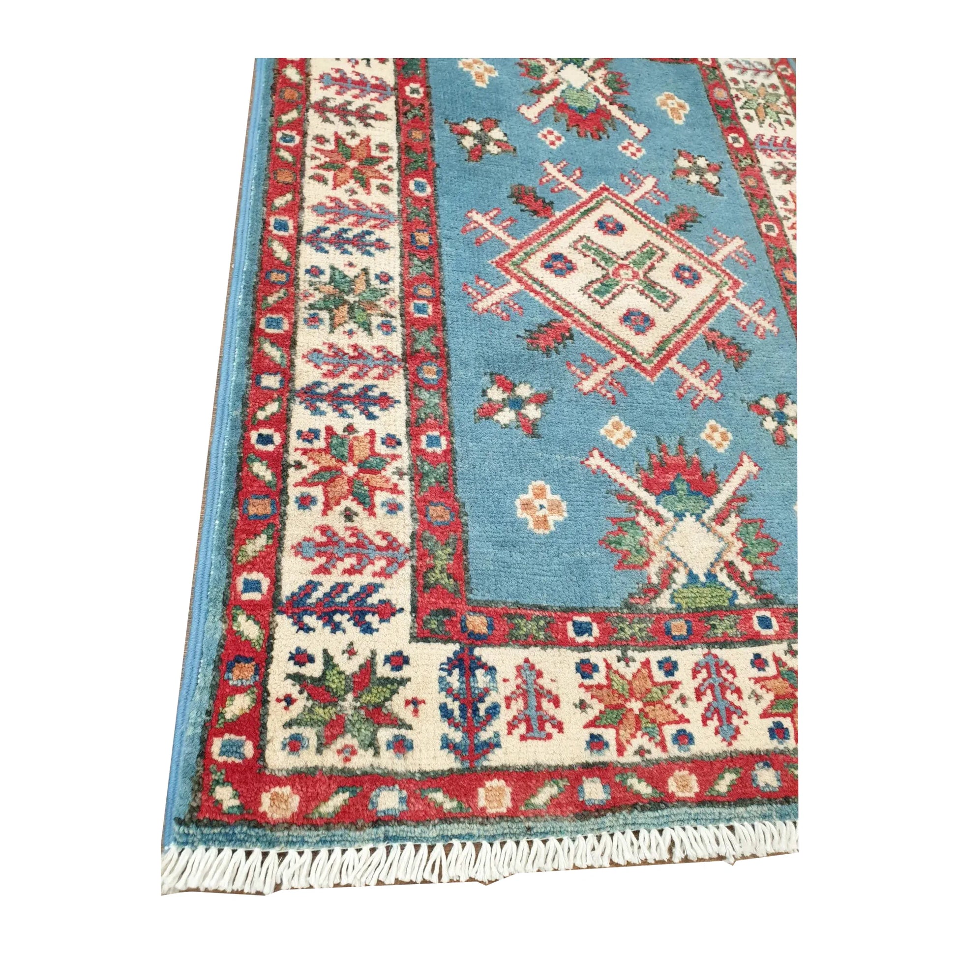 Angled corner detail of Afghan Kazak rug showing blue field motifs, layered border and visible fringe