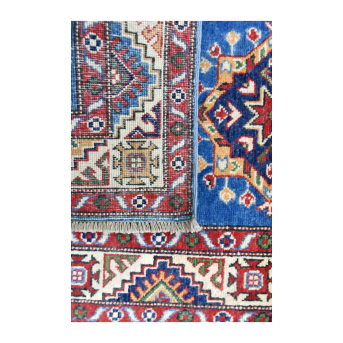 Folded-corner detail of Afghan Kazak runner showing the patterned reverse beside its blue front and multicoloured border