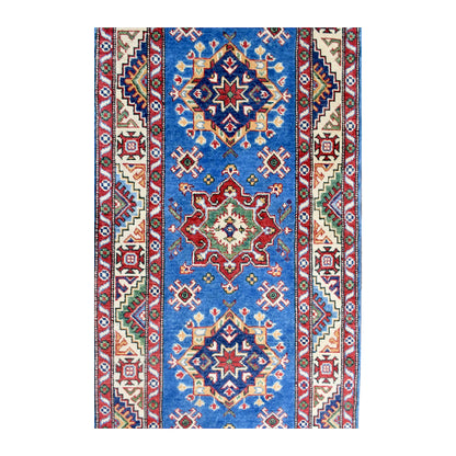 Field detail of Kazak runner showing red and navy medallions, smaller motifs and patterned borders around the blue field
