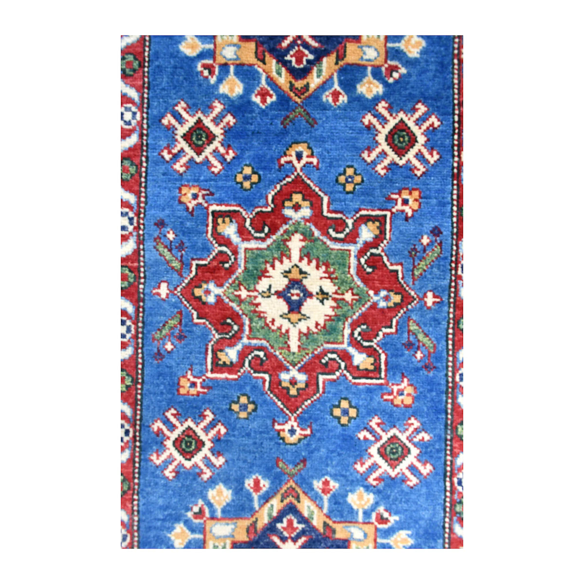 Close-up of a red stepped medallion with an ivory centre and smaller motifs on the Kazak runner’s blue field