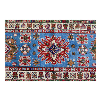 Overhead field detail of Afghan Kazak runner showing a large brick-red and ivory star medallion on sky blue