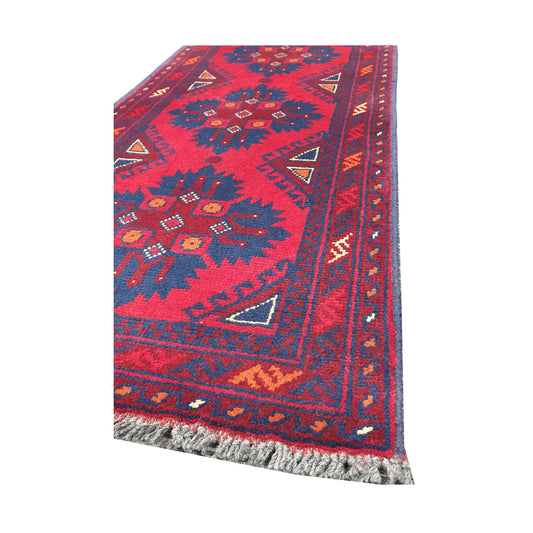 Angled corner and fringe view of Afghan Khal Mohammadi wool rug showing deep red field, dark blue motifs, border detail and light fringe